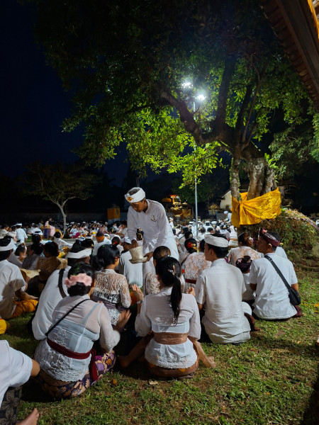 Ook in 2026 droegen vrouwen een witte kebaya en mannen een wit jasje bij het tempelfeest in de Pura Dalem in Budakeling. Na afloop van het ritueel ontvingen zij van de tempelpriester het door de goden gezegende water (of: wijwater). © Francine Brinkgreve