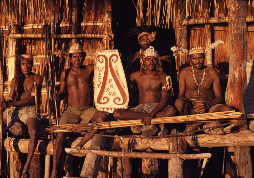 Asmat mannen tonen een schild waarop staat geschreven: 'West Papua Merdeka!' (Onafhankelijk Papoea), Warse, 2003. (TM-20041255) Fotograaf: Wim van Oijen. © Tropenmuseum/Nationaal Museum van Wereldculturen