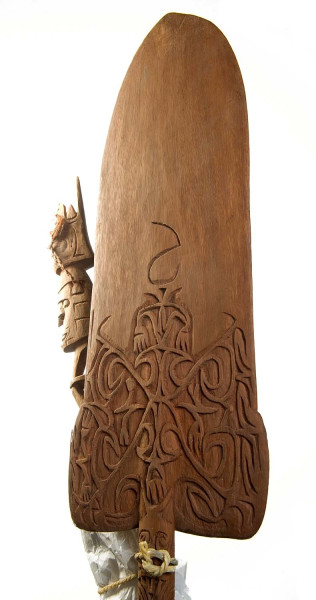 Het bovenste gedeelte van een peddel is soms versierd. Deze peddel is versierd met zes mensenhoofden met bosjes vezels in de oren, en een jaarvogelkop met casuarisveertjes. Asmat-regentschap, 1943-1953. (TM-2229-21) 