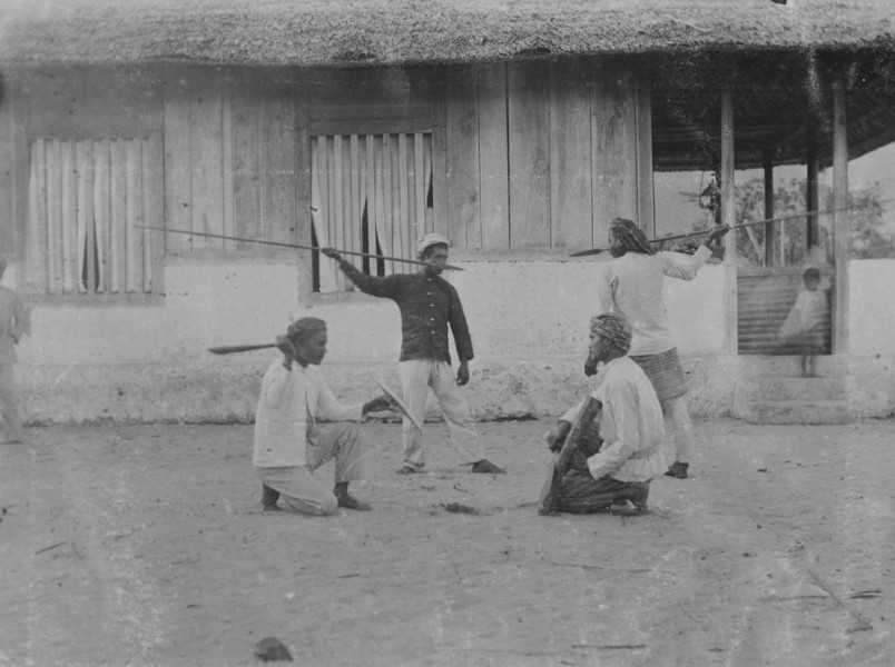 Demonstratie van speerwerpen en vechten met zwaard en schild door mannen in een dorp op het eiland Buru, 1905-1920. Fotograaf onbekend. (TM-60045885)
