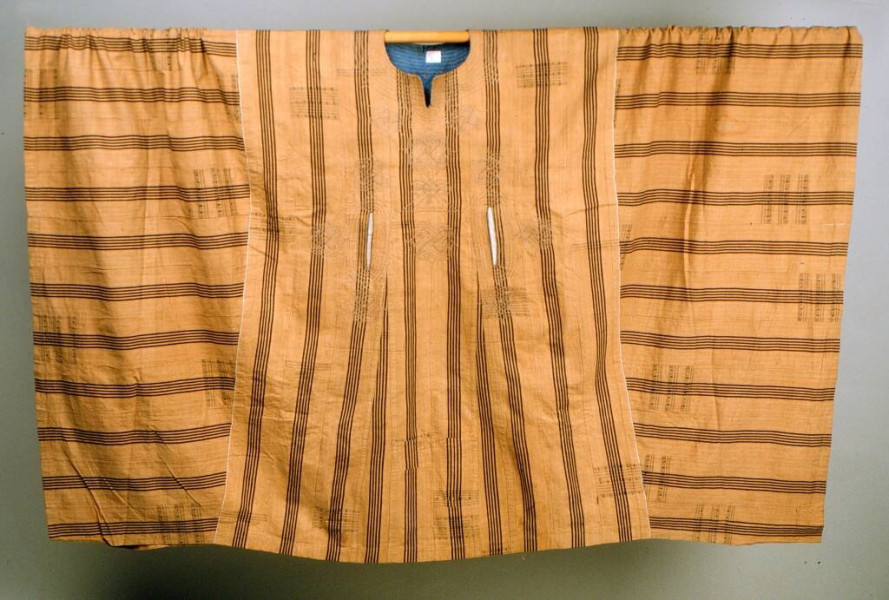 Gele katoenen boubou uit Nigeria. De stof is versierd met verticale clusters van bruine strepen. Het heeft twee zakopeningen. (WM-70089)