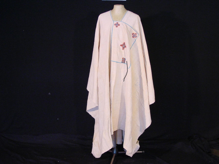 Witte katoenen boubou. De voorzak is versierd met dunne blauwe lijnen en bloemenborduursels in rood, blauw, lichtblauw en paars. Het is gemaakt in de eerste helft van de 20e eeuw, in Burkina Fasso. (TM-3981-329)