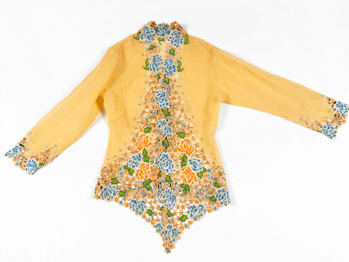 Kebaya Nyonya, een gele kebaya waarbij de voorkant in een punt uitloopt, Singapore, voor 1993. Met geel, groen en blauw borduurwerk (pioenrozen). (TM-5528-16)